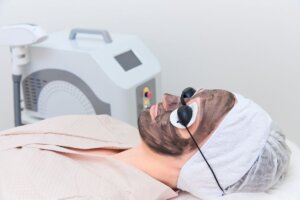 woman at clinic having a carbon facial wearing goggles